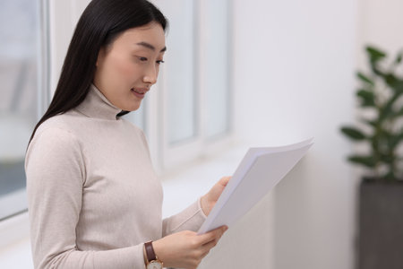 Portrait of smiling businesswoman with documents in officeの写真素材