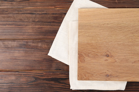 Cutting board and napkin on wooden table, top view. Space for textの写真素材