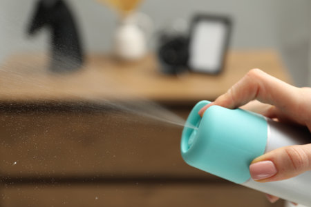 Woman spraying air freshener at home, closeup. Space for text