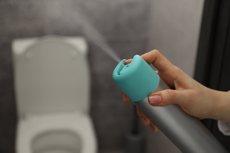 Woman spraying air freshener at home, closeup. Space for text