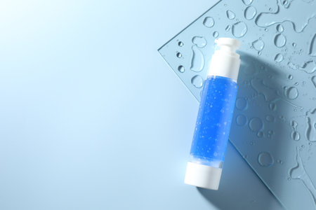 Bottle of cosmetic product on light blue background, top view. Space for textの写真素材