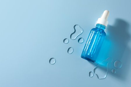 Bottle of cosmetic serum on light blue background, top view. Space for textの写真素材