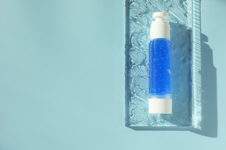 Bottle of cosmetic product on light blue background, top view. Space for textの写真素材