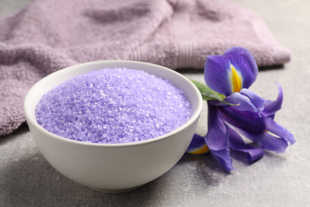 Natural sea salt in bowl, towel and beautiful flower on gray table, closeupの写真素材