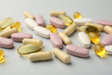 Different vitamin pills on light gray background, closeup. Health supplement