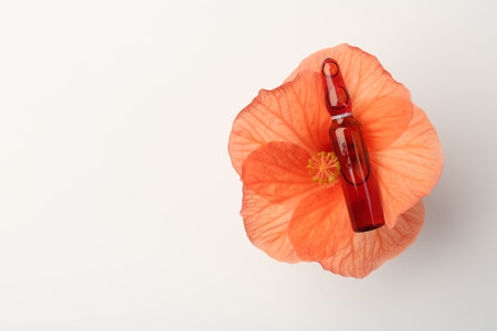 Skincare ampoules and hibiscus flower on white background, top view. Space for textの写真素材