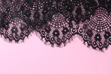 Black lace on pink background, top view. Space for textの写真素材