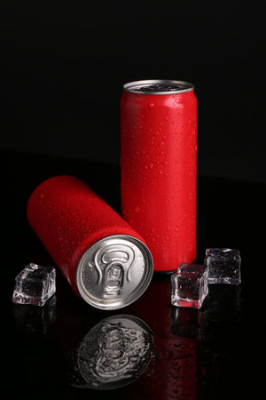 Energy drinks in wet cans and ice cubes on black background