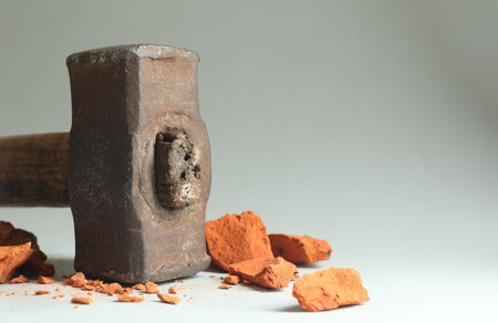 One sledgehammer and pieces of broken brick on gray background, closeup. Space for textの写真素材