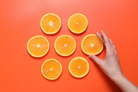 Woman with slices of juicy orange on terracotta background, top viewの写真素材
