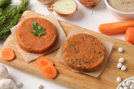 Uncooked carrot cutlets and ingredients on white wooden table. Vegetarian productの写真素材