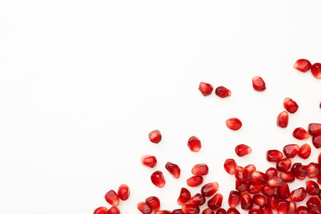 Many ripe juicy pomegranate grains on white background, flat lay. Space for textの写真素材