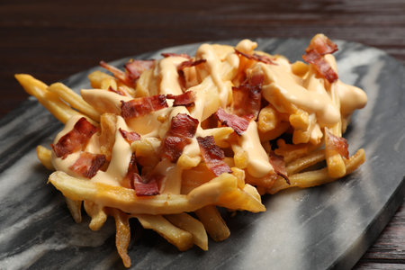 Delicious French fries with bacon and cheese sauce on table, closeupの写真素材