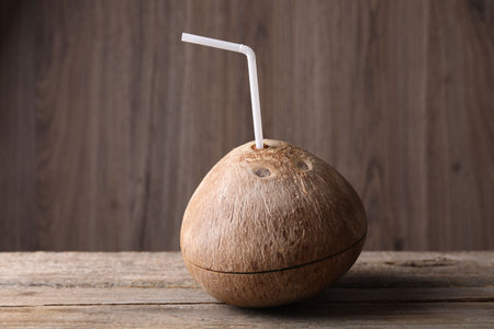 Coconut water. Fresh nut with straw on wooden tableの写真素材