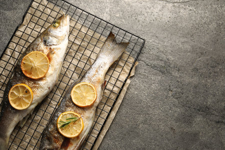 Baked fish with lemon on gray textured table, top view. Space for textの写真素材
