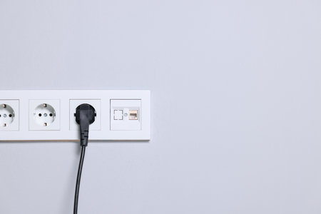 Power sockets and electric plug on gray wall, space for textの写真素材