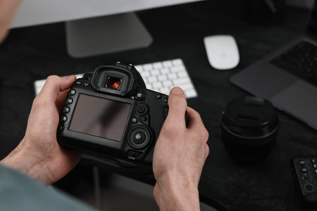 Photographer holding camera near dark table, closeupの写真素材