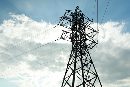 Telephone pole and wires against blue sky with clouds