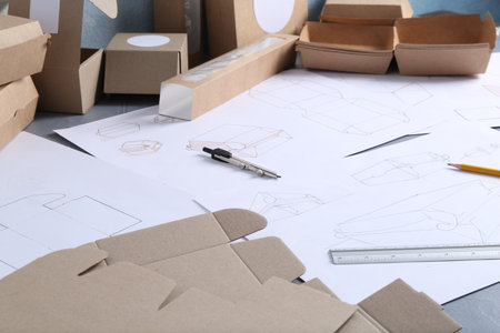 Creating packaging design. Drawings, boxes and stationery on table, closeup