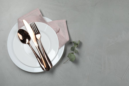 Stylish setting with elegant cutlery on gray table, top view. Space for text
