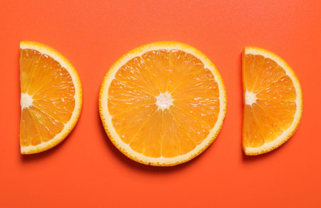 Slices of juicy orange on terracotta background, flat layの写真素材