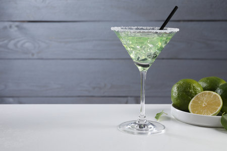 Delicious Margarita cocktail with ice cubes in glass and lime on white table, space for textの写真素材