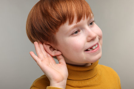 Little boy with hearing problem on grey backgroundの写真素材