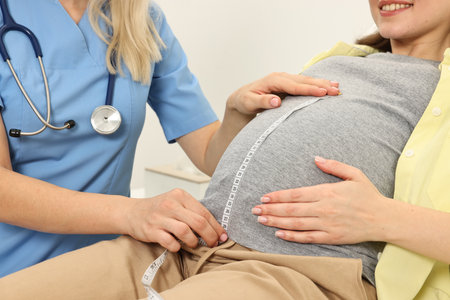 Pregnancy checkup. Doctor measuring patient's tummy in clinic, closeup