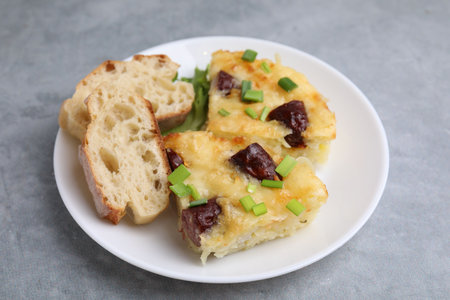 Tasty sausage casserole with green onion and bread on gray table, closeupの写真素材