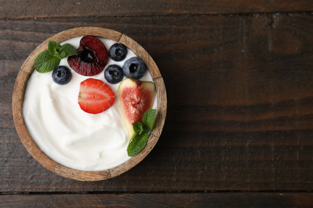 Bowl with yogurt, berries, fruits and mint on wooden table, top view. Space for textの写真素材