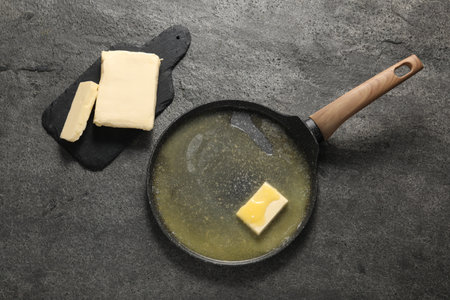 Melting butter in frying pan and dairy product on gray table, top viewの写真素材