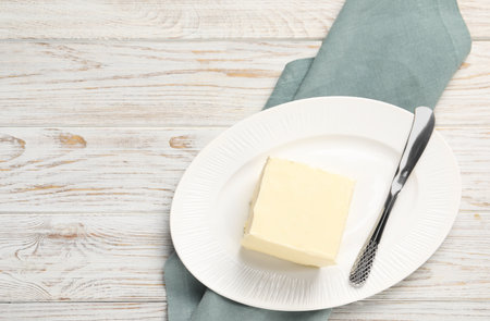 Block of tasty butter and knife on white wooden table. Space for textの写真素材