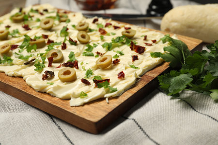 Fresh butter board with cut olives, sun-dried tomatoes and parsley on table, closeup