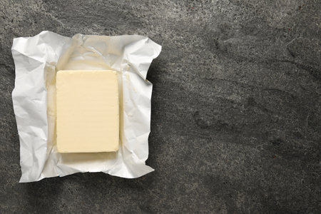 Block of tasty butter in open foil packaging on gray table, top viewの写真素材