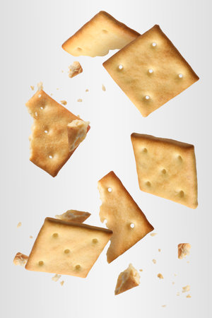 Tasty dry crackers falling on light gray backgroundの写真素材