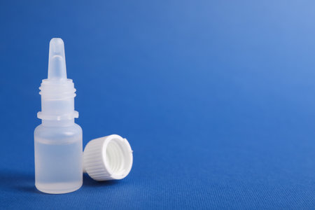 Bottle of medical drops on blue background, space for text