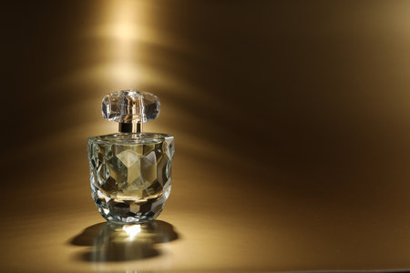 Luxury women's perfume. Sunlit glass bottle on golden background, space for textの写真素材