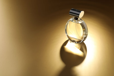 Luxury women's perfume. Sunlit glass bottle on golden background, space for textの写真素材