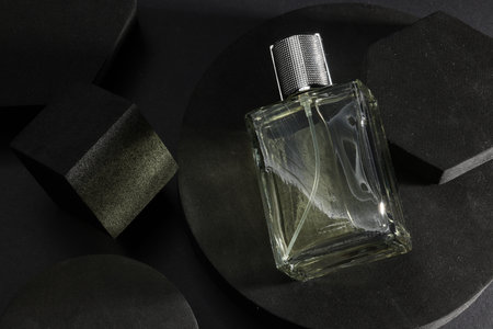 Stylish presentation of luxury men`s perfume in bottle on black background, top view. Space for text