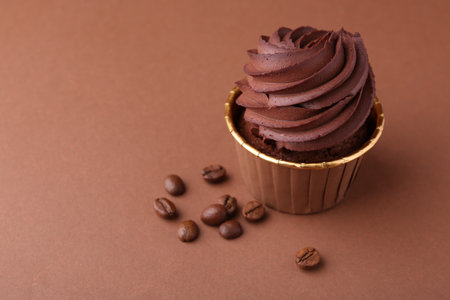Delicious chocolate cupcake and coffee beans on brown background, closeup. Space for textの写真素材