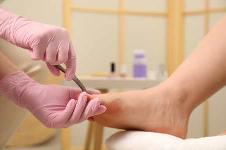 Professional pedicurist cutting client`s toenails with clipper in beauty salon, closeupの写真素材