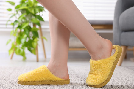 Woman in yellow soft slippers at home, closeup