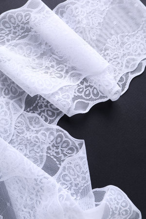 White lace on black background, top view