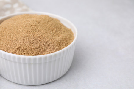 Dietary fiber. Psyllium husk powder in bowl on light gray table, closeup
