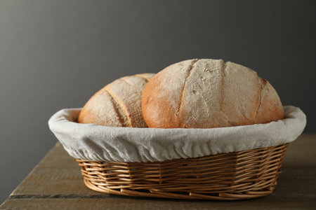 Wicker basket with fresh bread on wooden table