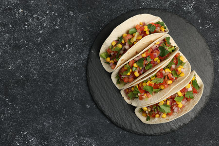 Tasty tacos with vegetables on black textured table, top view. Space for textの写真素材