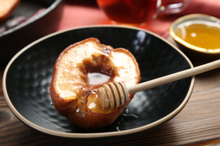 Tasty baked quince with honey in bowl on wooden table, closeupの写真素材
