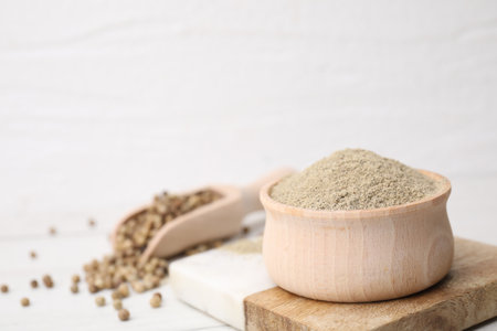 Aromatic spice. Ground pepper in bowl and scoop with peppercorns on white wooden table, closeup. Space for textの写真素材