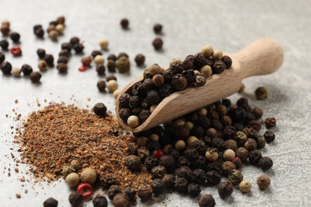 Aromatic spice. Ground and whole peppers in scoop on light gray table, closeup