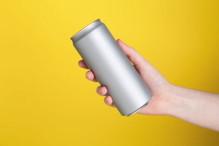 Woman with energy drink on yellow background, closeupの写真素材